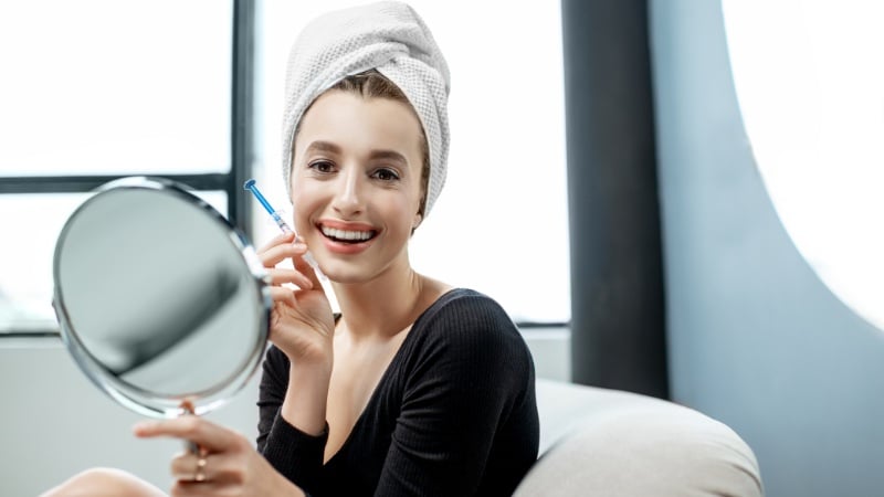 Une femme qui a bien respecté les instructions d'un fabricant de produit de blanchiment dentaire