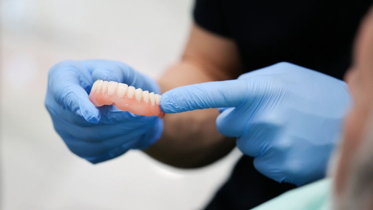 Un dentiste avec le dentier fixe d'un patient