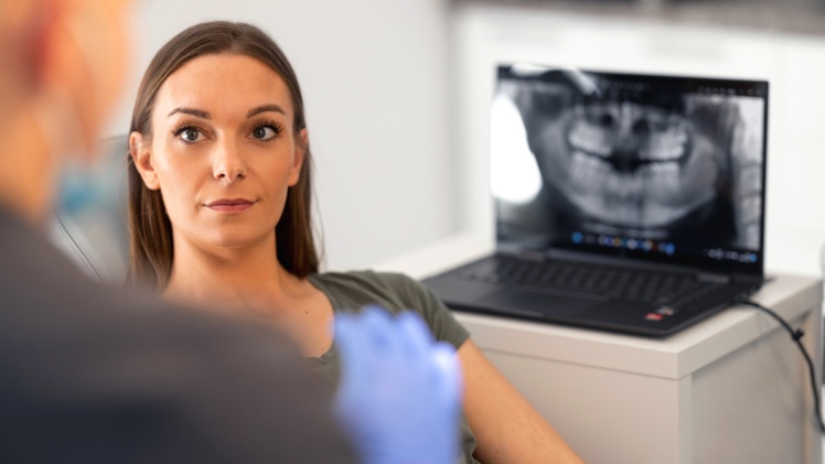 Un dentiste qui explique à une patiente le traitement par gouttière dentaire