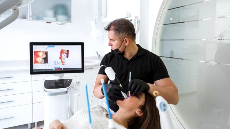 Un dentiste qui prend l'empreinte dentaire d'une patiente via un scanner 3D