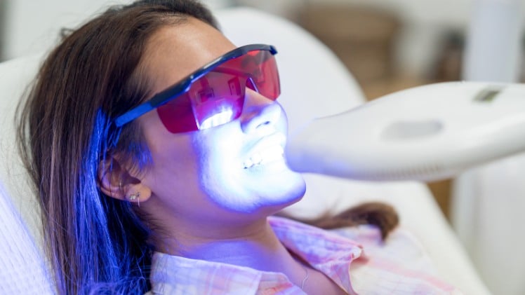 Une femme qui fait faire un blanchiment dentaire chez le dentiste