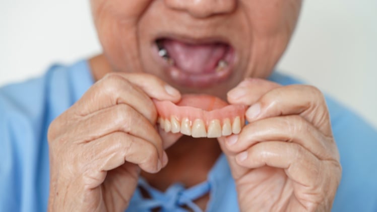 Une personne en train de mettre son dentier amovible